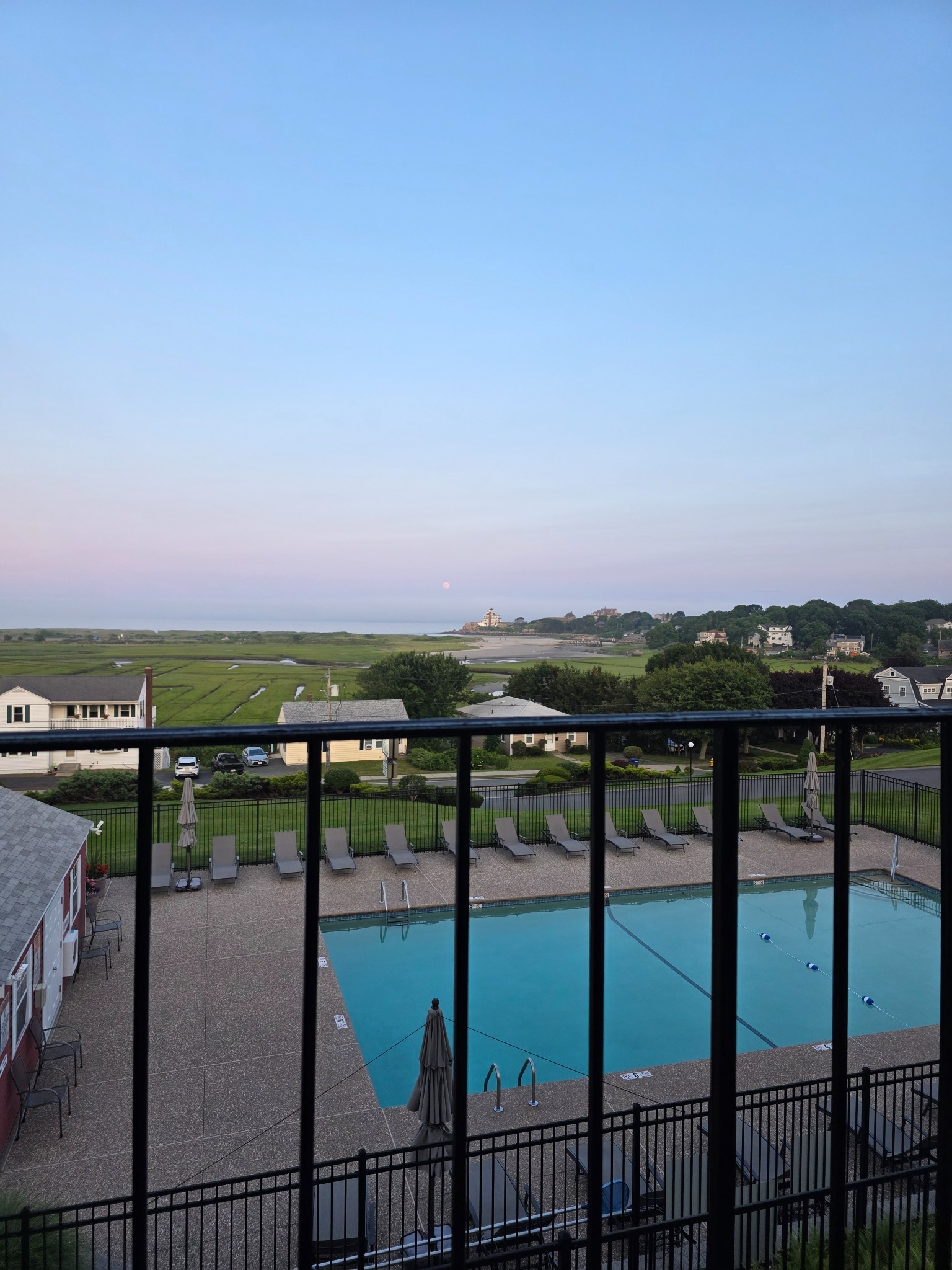 Balcony view over the hotel pool, marsh, beach, and moonrise in Gloucester, Massachusetts